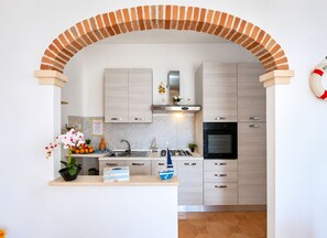 A modern kitchen with a brick archway, stainless steel appliances, and a small decorative sailboat.