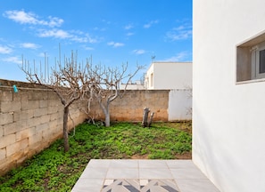 A courtyard with a tree, a brick wall, and a tiled patio. - Seaside Villa Golden Shell 1 (Porto Cesareo)