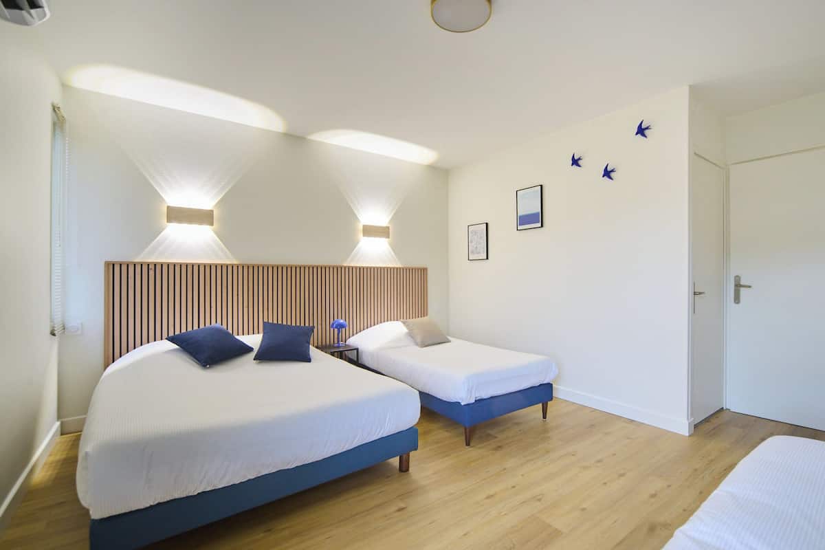 A hotel room with two beds, a wooden headboard, and a door.