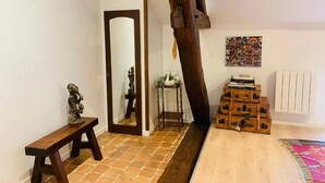 A room with a wooden bench, a mirror, a small statue, a radiator, and a stack of wooden boxes. - The colors of Commarin 2-bedroom apartment with kitchen. (Commarin)