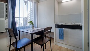 A compact kitchen with a dining area, a potted plant, and a view through the window. - CraftFlat Komagome 604 (豊島区)