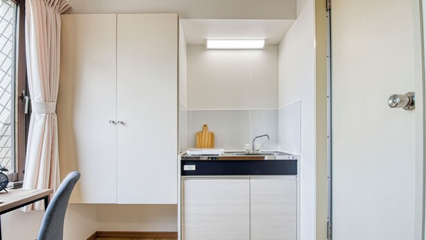 A compact kitchen with white cabinets, a black countertop, and a small sink. - CraftFlat Komagome 604 (豊島区)