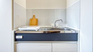 A compact kitchen with a built-in sink, a wooden cutting board, and a small countertop. - CraftFlat Komagome 604 (豊島区)