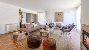 A modern living room with a sofa, coffee table, ottomans, and a fireplace. - Ge House by House and People (Caniçada)