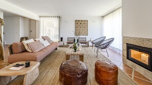 A modern living room with a sofa, ottomans, a coffee table, and a fireplace. - Ge House by House and People (Caniçada)