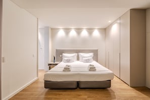 A modern bedroom with a large bed, built-in storage, and a minimalist design.