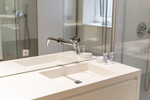A modern bathroom with a white sink, a mirror, and a glass shower enclosure.