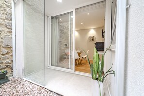 A modern room with a sliding glass door leading to an outdoor area with a dining table and chairs.