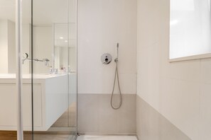 Um banheiro moderno com box de vidro, vaso sanitário visível e área de pia.
