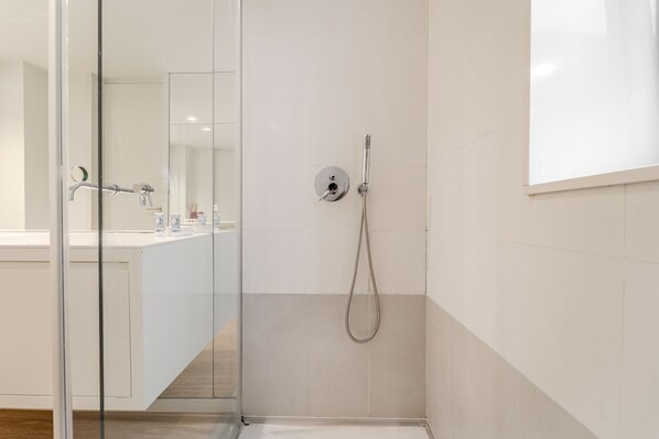 Un baño moderno con cabina de ducha de vidrio, inodoro a la vista y zona de lavabo.