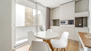 A modern kitchen with white cabinets, a round dining table, and white chairs. - Sé inn 4 by House and People (Braga)