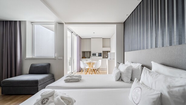 Ett hotellrum med en säng, en soffa, ett matbord och ett litet kök.