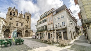 Ett torg med kullerstenar, utomhusservering och en historisk byggnad med utsmyckad arkitektur.