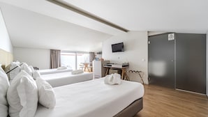 A hotel room with two beds, a desk, a television, and a wardrobe.