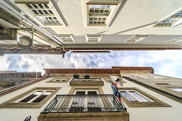 A building with multiple windows, a balcony with ornate railings, and a flag.
