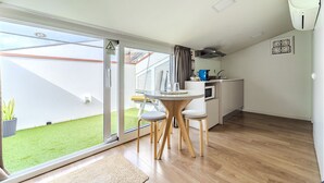 A modern kitchen with a dining area, a sliding glass door to a garden, and a small outdoor seating area.