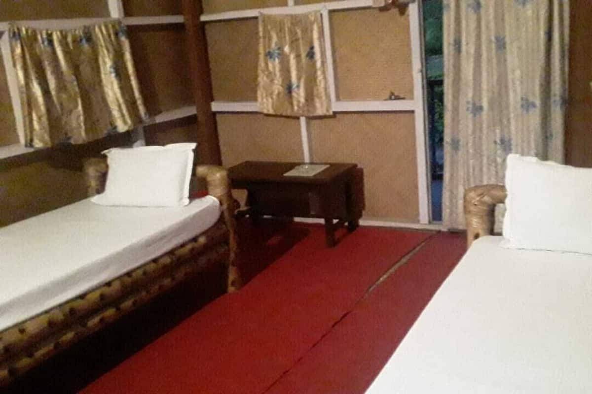 A room with two single beds, a small table, and a chair.
