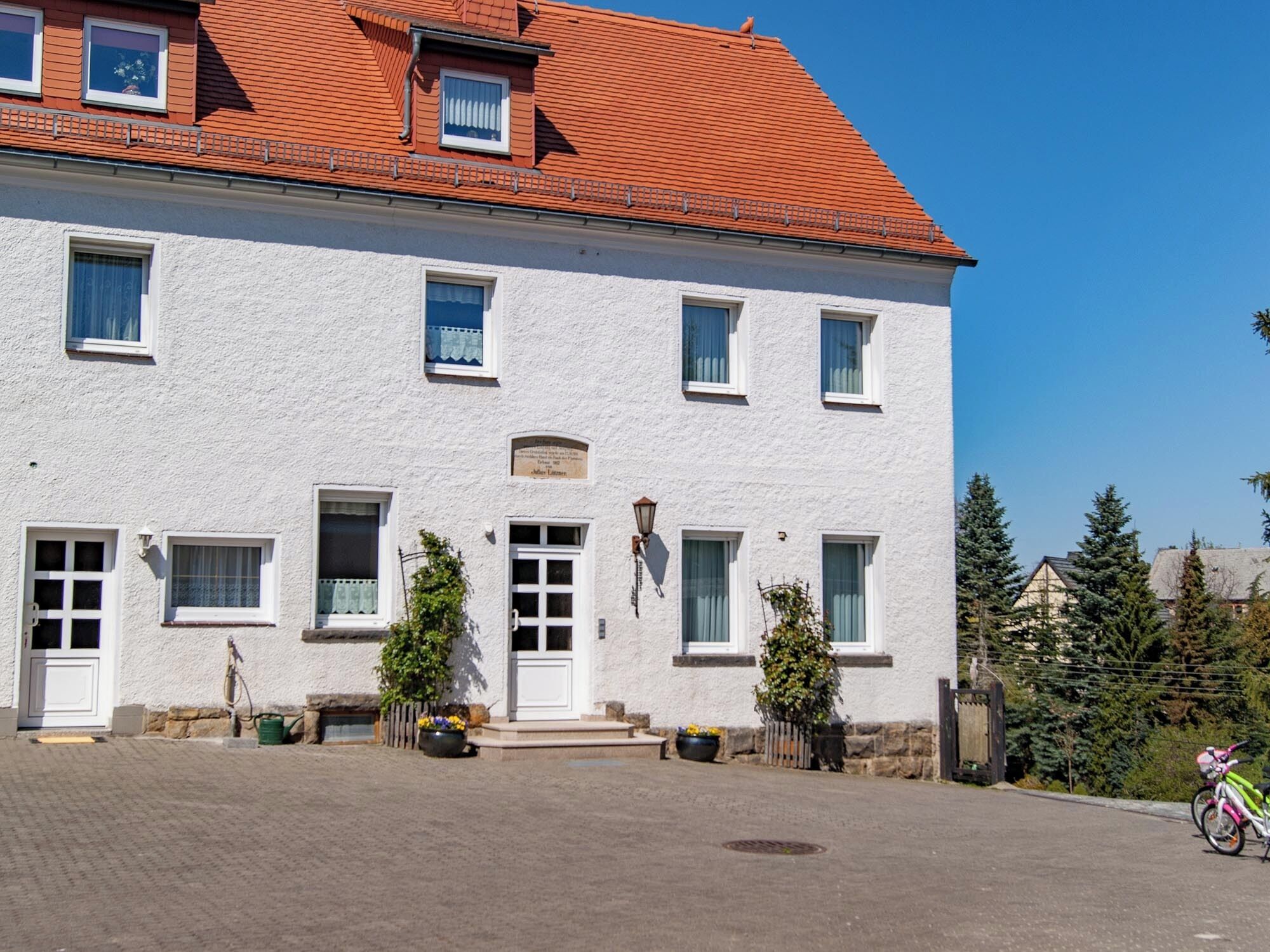 A two-story building with a red-tiled roof, white exterior walls, and multiple windows.