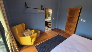 A room with a bed, a yellow armchair, a small table, a mirror, and a wooden wardrobe. - Zuu Tee Organic Farm & Roastery (Pai)