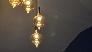Three hanging light fixtures with exposed bulbs against a dark background. - Zuu Tee Organic Farm & Roastery (Pai)
