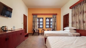 A hotel room with two beds, a TV mounted on the wall, a wooden cabinet, and a window with curtains. - Amara Palace (Phnom Penh)