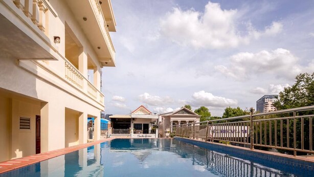 A swimming pool with a view of a hotel building and a sign for a restaurant. - Amara Palace (Phnom Penh)