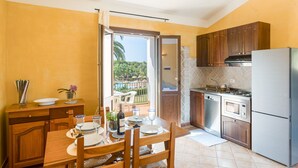 A kitchen with wooden cabinets, a stainless steel refrigerator, and a dining area with a table set for four. - Bernardini Tropical Residence Apartment (Pula)