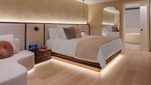 A modern bedroom with a large bed, bedside tables, a bedside lamp, and a mirror on the wall.