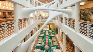 A multi-level atrium with a central green pathway, white railings, and a bar area on the left.