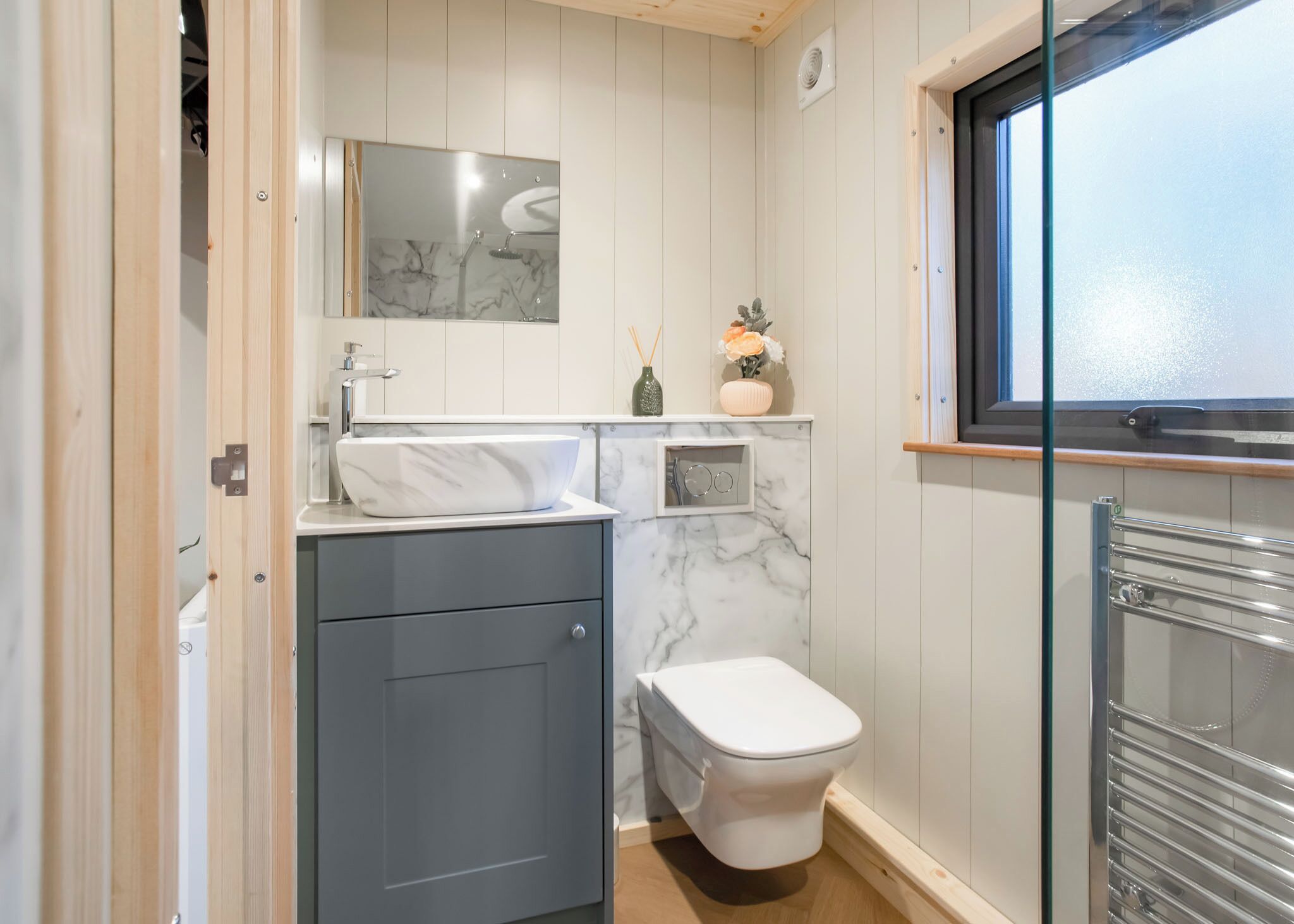 Une petite salle de bain avec un lavabo en marbre, des toilettes, un miroir et une fenêtre.