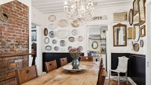 Un comedor con mesa de madera, sillas, una lámpara de araña y una pared de ladrillo.