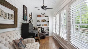 Una sala de estar acogedora con un sofá capitonado, un mueble negro y un ventilador de techo.