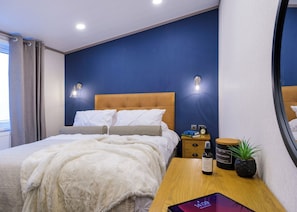 Ein Schlafzimmer mit Bett, Nachttischen, einem Spiegel und einem Fenster.