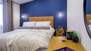 Ein Schlafzimmer mit Bett, Nachttischen, einem Spiegel und einem Fenster.