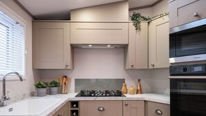 Eine moderne Küche mit beigen Schränken, einem eingebauten Kochfeld und einem schwarzen Backofen.
