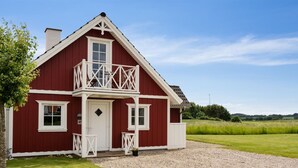 A two-story red house with a balcony, a gravel driveway, and a grassy field in the background. - "Sakari" - 375m from the sea by Interhome (Brenderup Fyn)