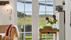 A cozy room with a sofa, a table with a vase of flowers, and a view of a garden through a large window. - "Sakari" - 375m from the sea by Interhome (Brenderup Fyn)