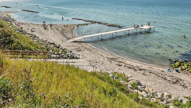A beach with a wooden pier extending into the water, surrounded by rocks and clear blue sea. - "Sakari" - 375m from the sea by Interhome (Brenderup Fyn)