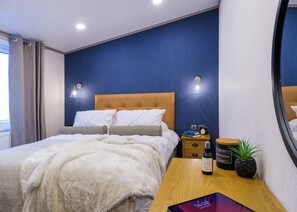 Ein Schlafzimmer mit Bett, Nachttischen, einem Spiegel und einem Fenster.