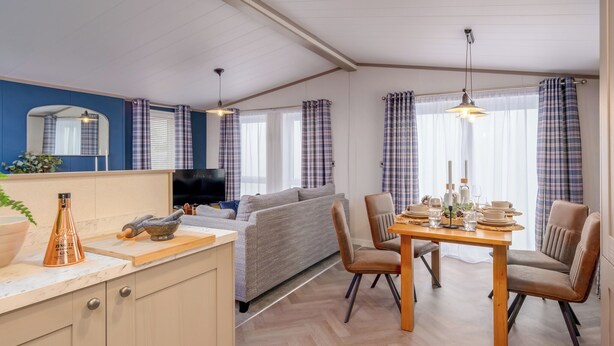 A modern living room with a sofa, dining table, and kitchen area. - Deluxe modern and contemporary luxury lodge perfect for a relaxing escape. (Workington)