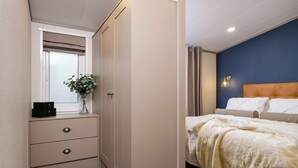 A bedroom with a bed, a nightstand, a dresser, and a window with curtains. - Deluxe modern and contemporary luxury lodge perfect for a relaxing escape. (Workington)