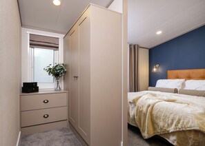 A bedroom with a bed, a nightstand, a dresser, and a window with curtains. - Deluxe modern and contemporary luxury lodge perfect for a relaxing escape. (Workington)
