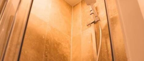 Une douche équipée d’un pommeau de douche carré et d’un pommeau de douche amovible fixé au mur.