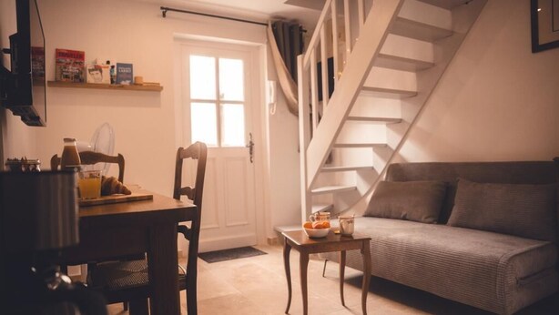 A cozy living room with a sofa, a dining table with chairs, and a staircase.