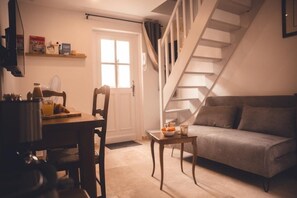 A cozy living room with a sofa, a dining table with chairs, and a staircase. - The Lord of the Rings, Lamartine (Tours)