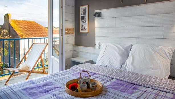 Une chambre à coucher avec un lit, une table de chevet, une chaise et un balcon.