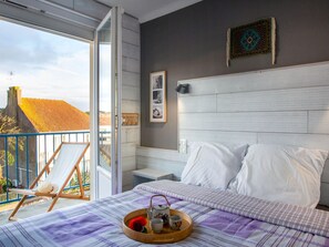 Ein Schlafzimmer mit Bett, Nachttisch, Stuhl und Balkon.