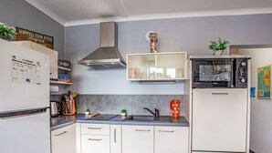 Une cuisine moderne avec des armoires blanches, des appareils en acier inoxydable et un pare-feu gris.