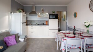 Une cuisine compacte avec des meubles blancs, un four à micro-ondes et un luminaire moderne.