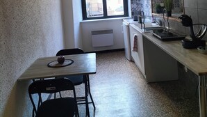 A compact kitchen with a wooden ceiling, a window, a sink, and a dining area with a chair and table. - Pet-friendly apartment le petit paradis :) (Saint-Pons-de-Thomières)